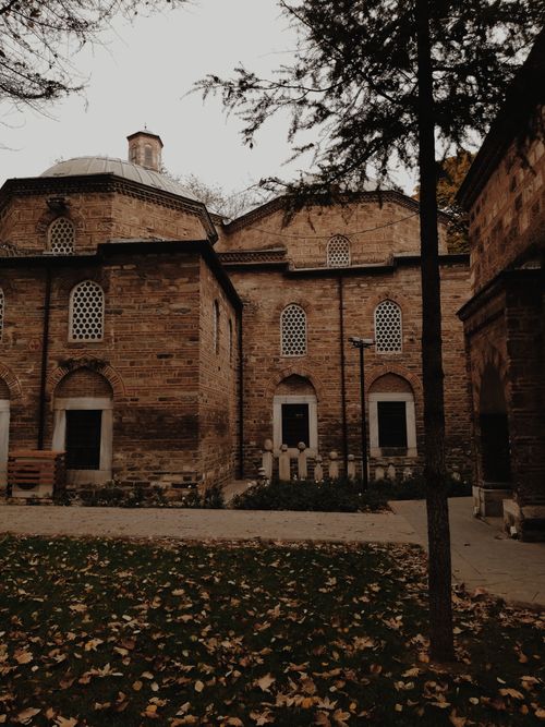 Free Explore the charm of historical brick structures surrounded by a serene leafy courtyard, perfect for travel enthusiasts. Stock Photo