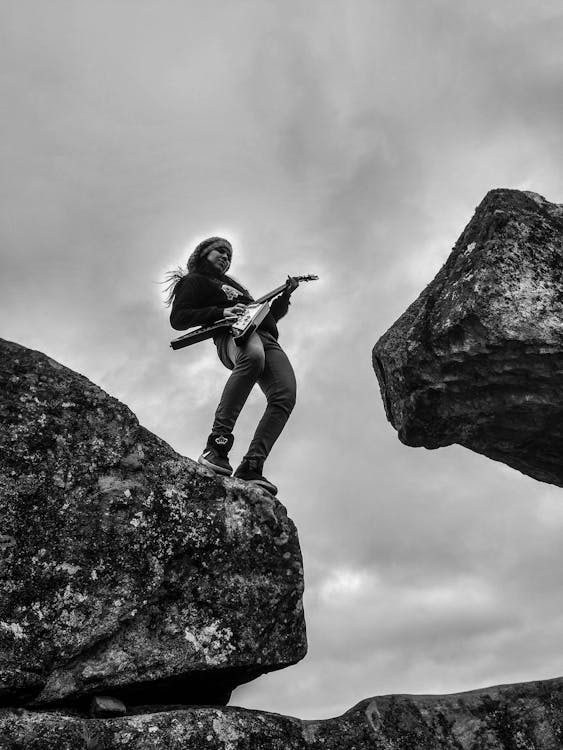 岩層の上でエレキギターを弾く女性