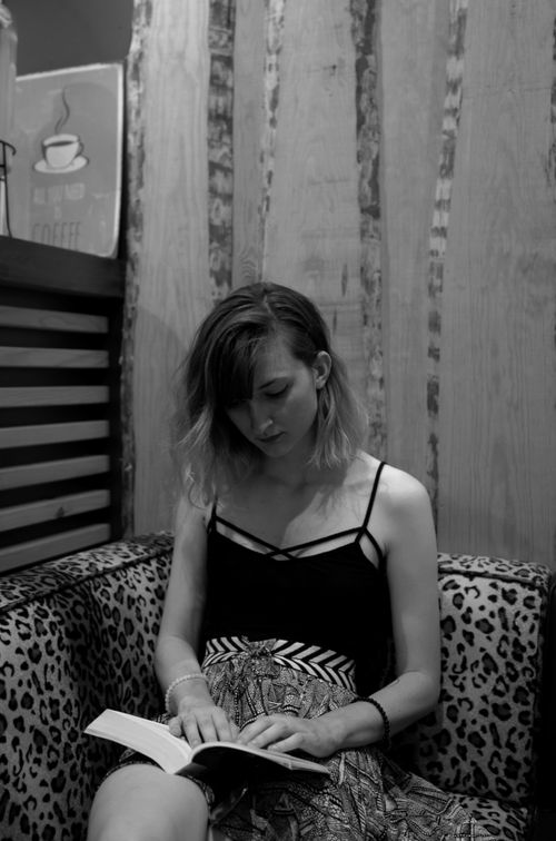 Free Black and white portrait of a woman reading in a stylish cafe with leopard print seating. Stock Photo