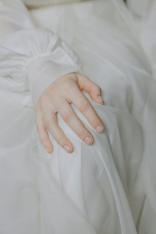 Close-up of Hand of a Woman in a White Dress Lying on the Knee