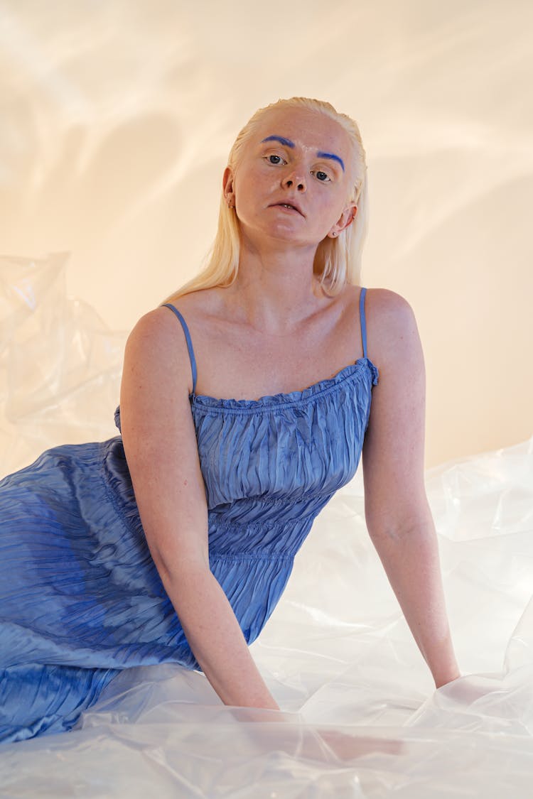 Woman With Blue Eyebrows Wearing Dress Sitting On Foil