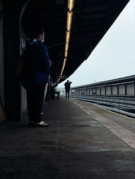 People waiting at an urban train station during a cloudy day, capturing the mood of transit.