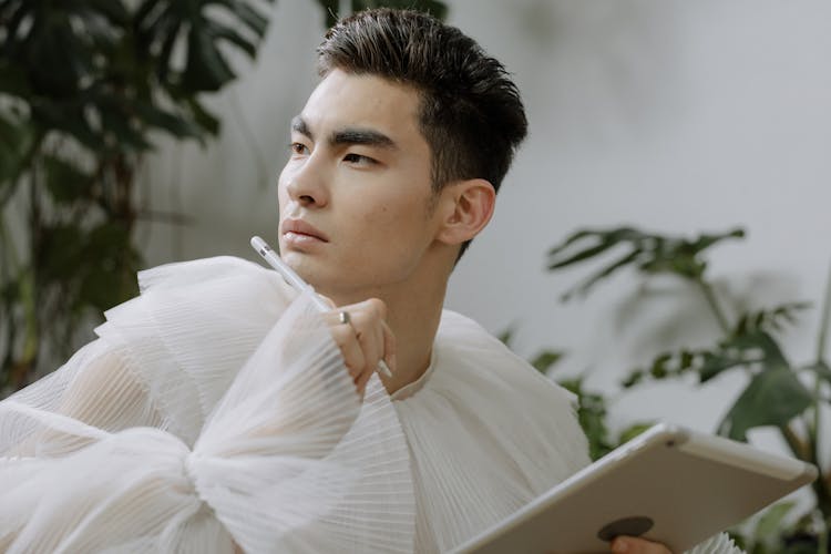 A Man In White Long Sleeves Holding A Pen And A Tablet