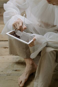 A woman elegantly sketches on a digital tablet with a stylus, showcasing technology and creativity.