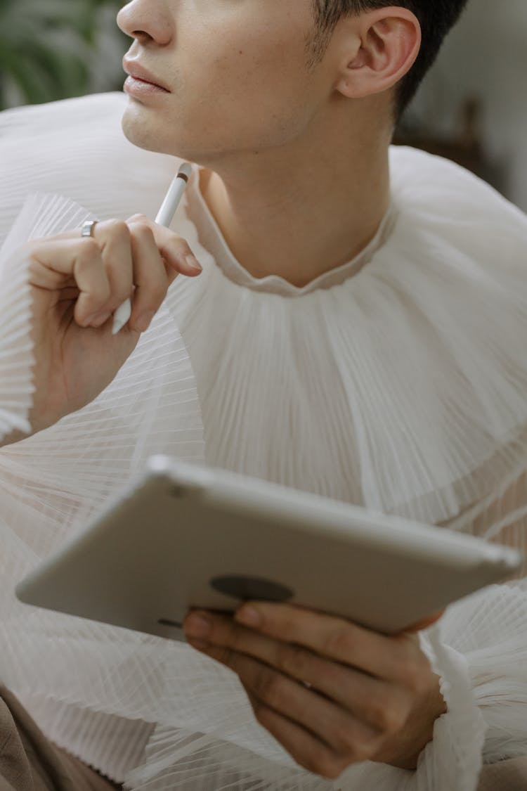 A Man In White Long Sleeves Holding A Pen And Tablet