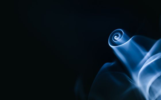 Captivating image of blue smoke forming a mesmerizing swirl on a dark background.