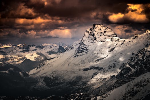 Snow-covered mountain peaks in Italy under dramatic sunset skies, perfect for nature photography.