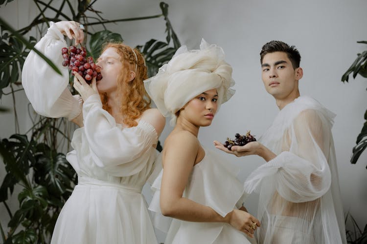 People Wearing White Outfit Standing Near Green Plants While Posing At The Camera