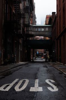 A moody, empty street in New York City featuring architectural connections and industrial vibes.