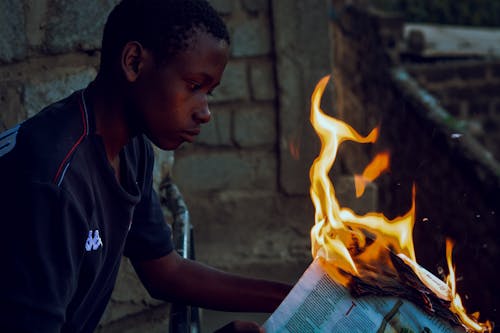 Free Boy Holding a Burning Newspaper Stock Photo