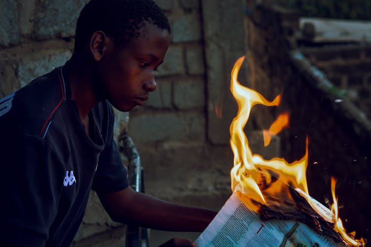 Boy Holding A Burning Newspaper