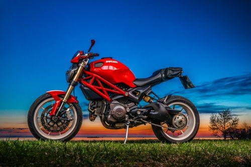 Free A parked red Ducati motorcycle captured at twilight with a vivid, colorful sky backdrop. Stock Photo