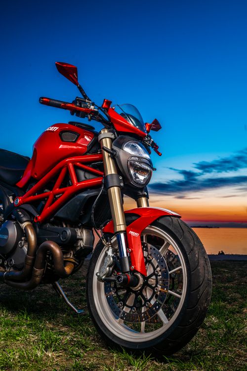 Free Closeup of a red motorcycle against a vibrant sunset sky. Stock Photo