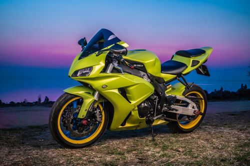 Free A neon green motorbike parked on a grassy area during a vibrant sunset by the lake. Stock Photo