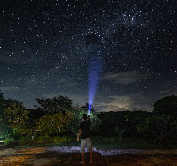 Man Looking At Stars At Night With Flashlight