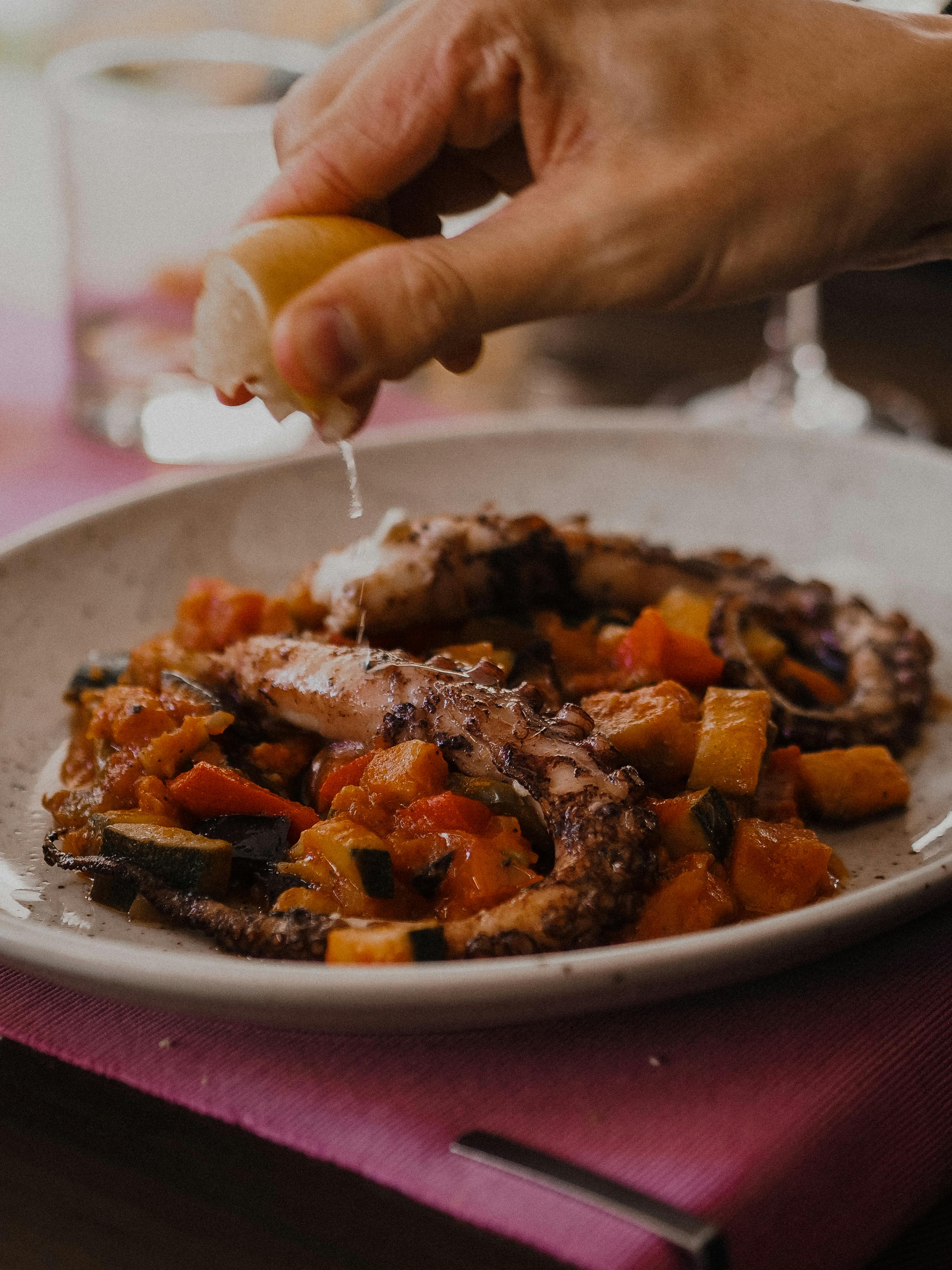 Person Squeezing Lemon on his Food