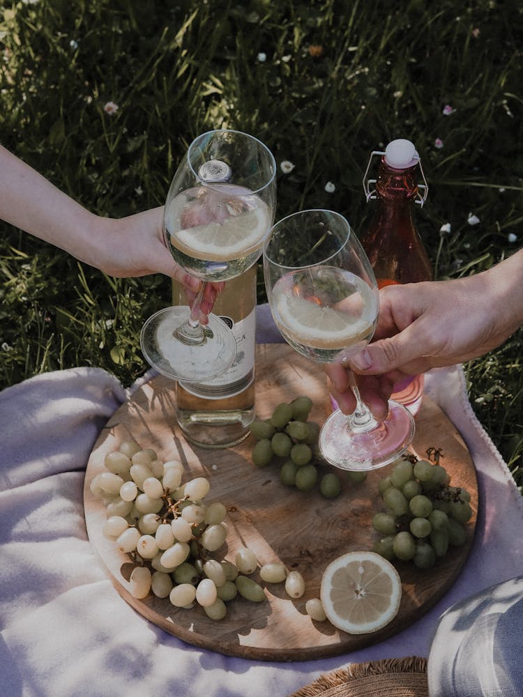 Hands Holding Glasses Over Tray With Grapes