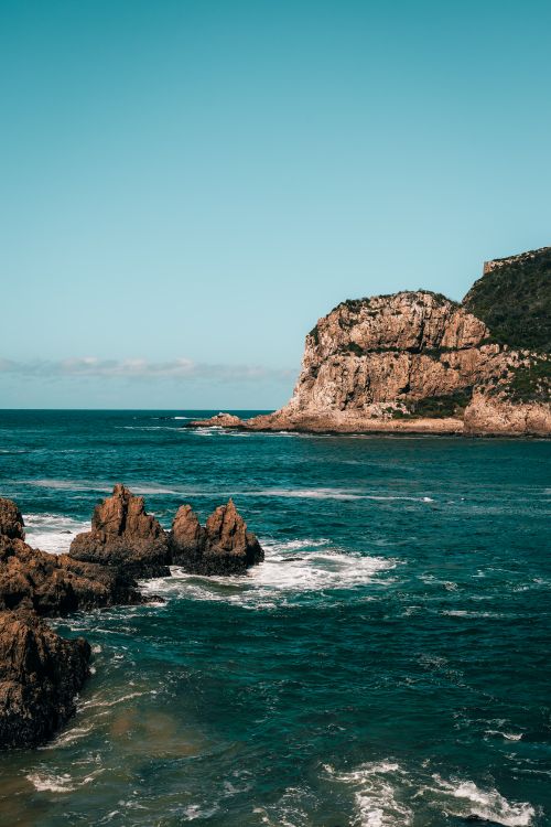 Free Scenic view of rocky cliffs and turquoise ocean waves under a clear blue sky, captured during the day. Stock Photo