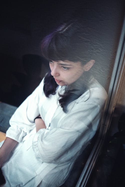 Melancholic teenage girl with dark hair in white shirt