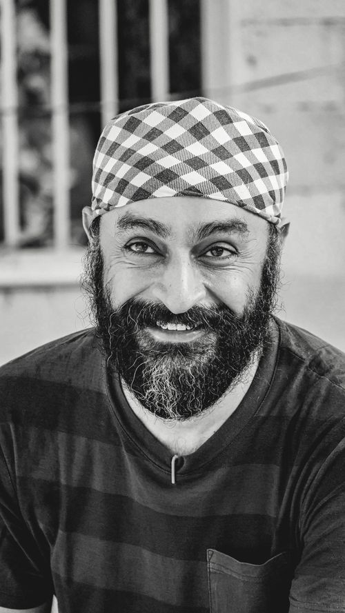 Free Bearded man in a checkered headscarf smiling at the camera in monochrome. Stock Photo
