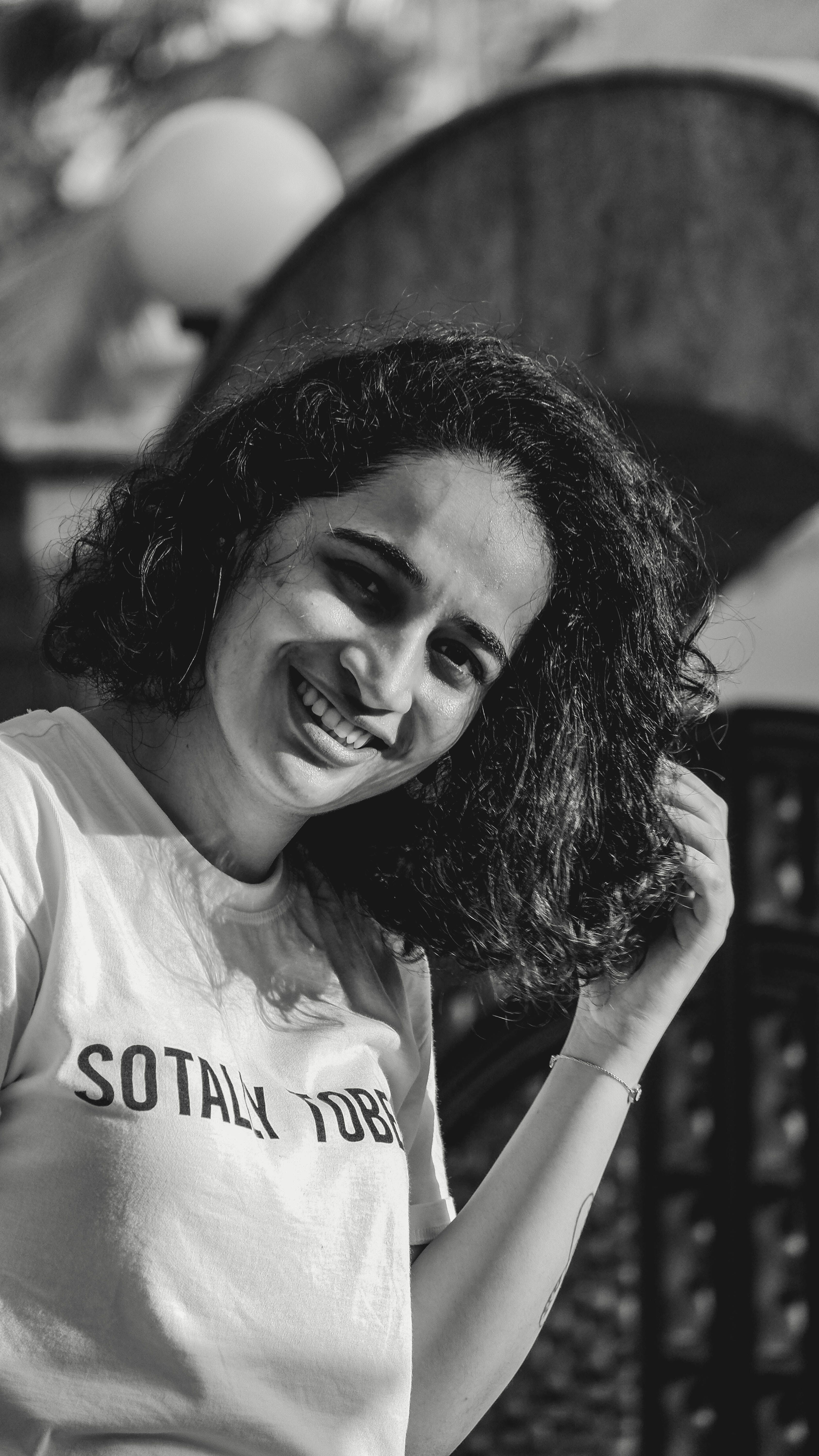 Happy woman with curly hair smiling in a black and white portrait.