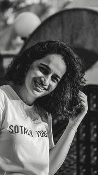 Happy woman with curly hair smiling in a black and white portrait.