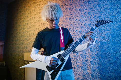 Free A young musician performs on an electric guitar indoors with stylish lighting. Stock Photo
