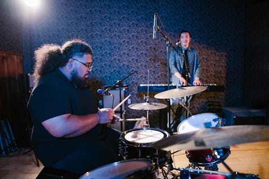 Two musicians - a drummer and keyboardist - performing in an intimate studio setting.