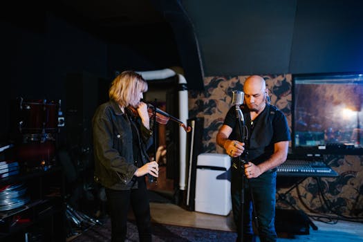 Two musicians tune instruments in a dimly lit studio for a live performance.