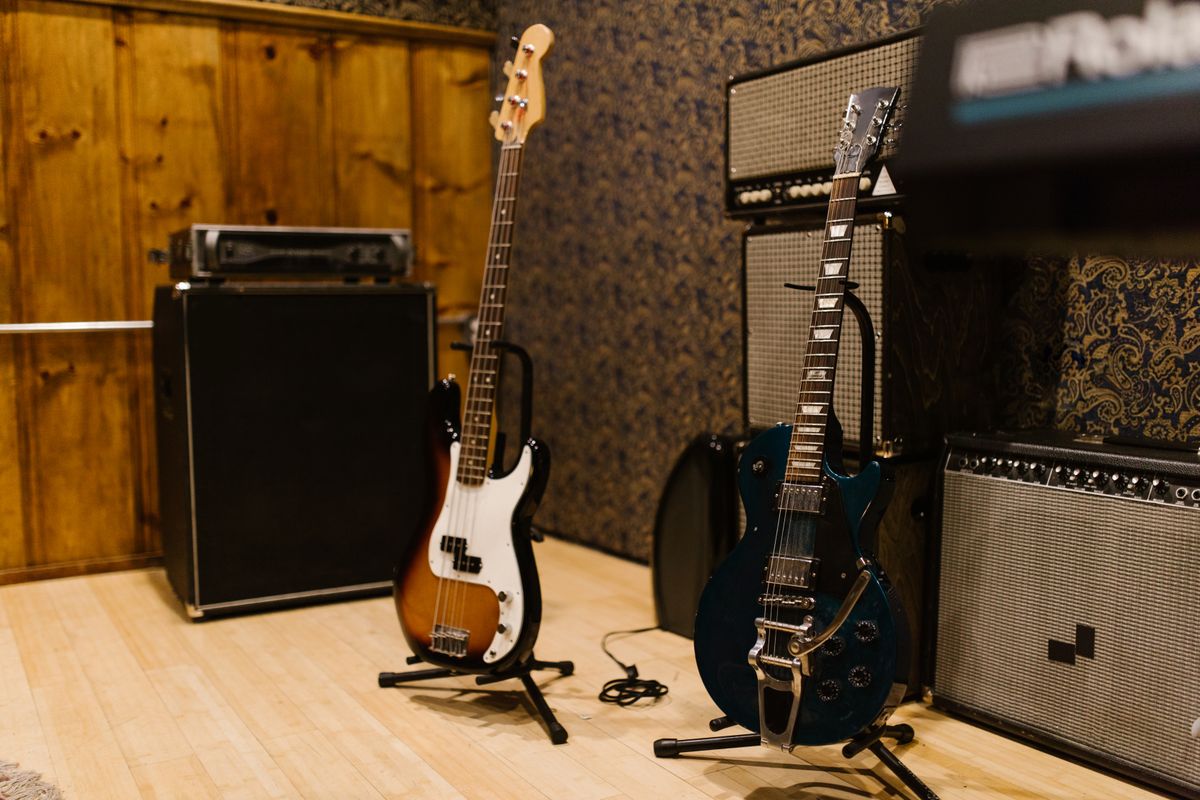 An electric guitar and bass guitar standing beside their amplifiers in a studio