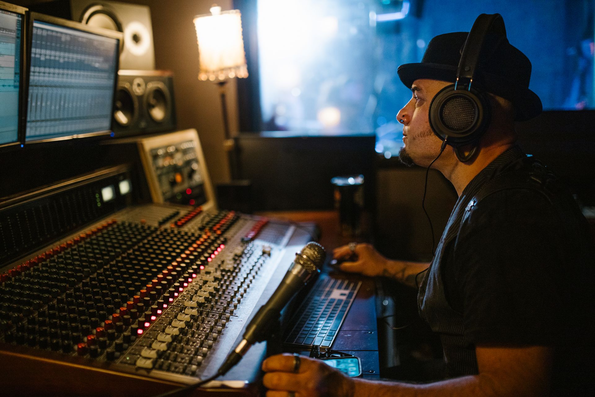 A music producer wearing headphones works at a mixing console in a recording studio.