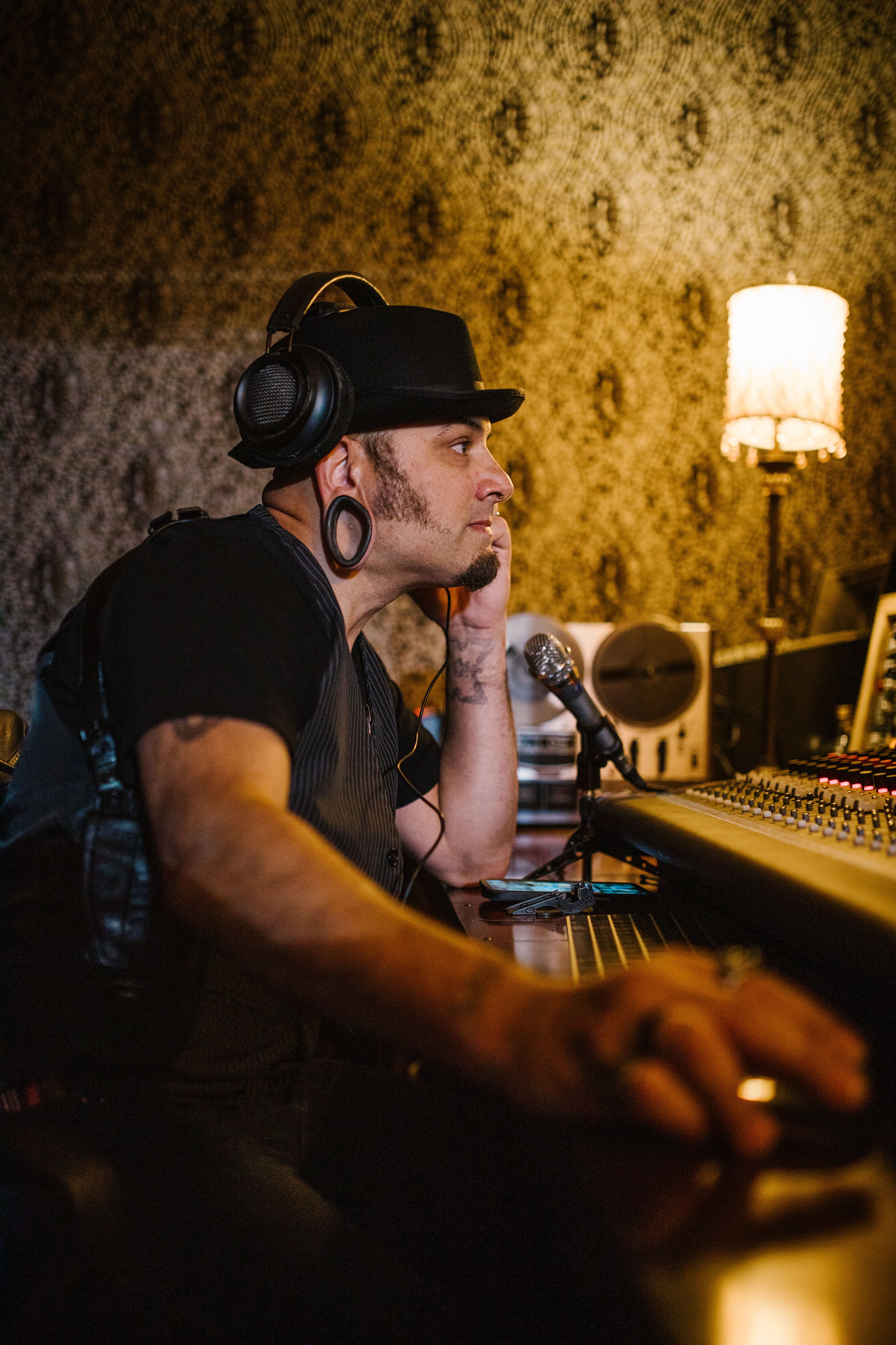 Focused music producer adjusting sound mixer in a stylish studio with headphones on.