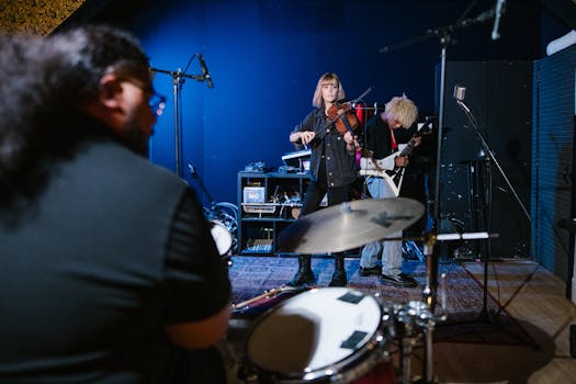 Band rehearsal with violin, guitar, and drums in an indoor studio.