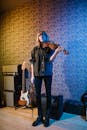 Woman in Blue Denim Jacket and Black Pants Playing Violin