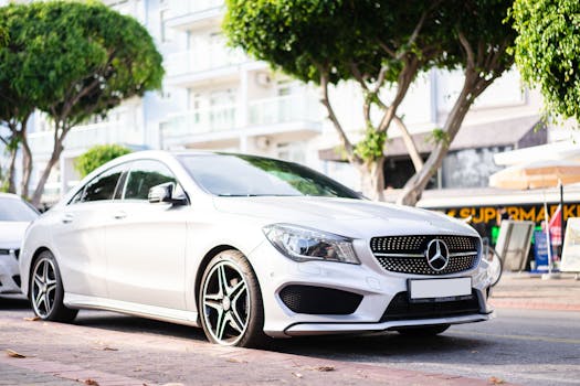 Elegant white Mercedes Benz car parked on a sunny urban street.