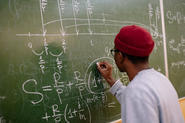 Back View Of A Student Answering A Problem On The Chalkboard