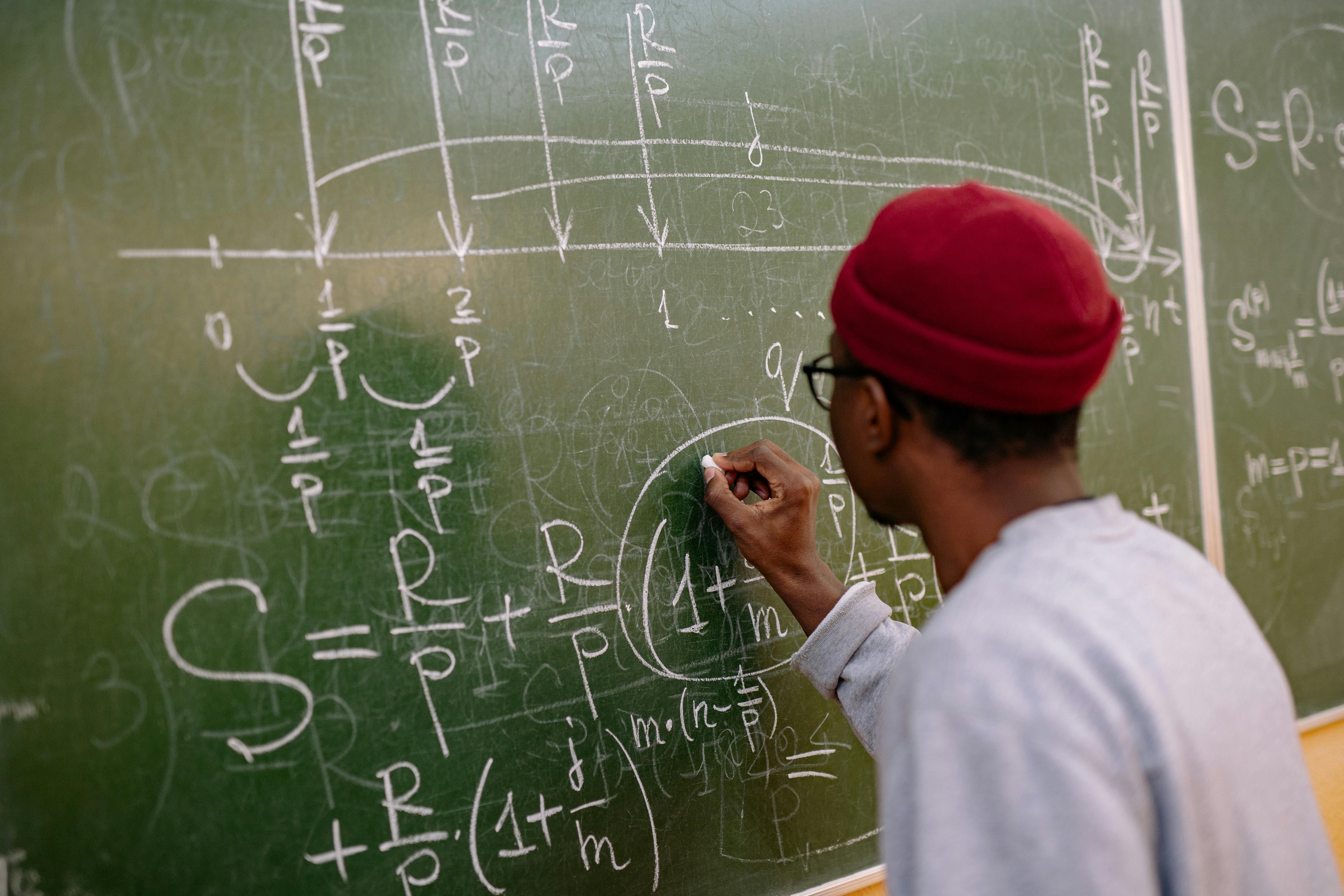 Hand Writing Mathematical Formulas on a Blackboard · Free Stock Photo