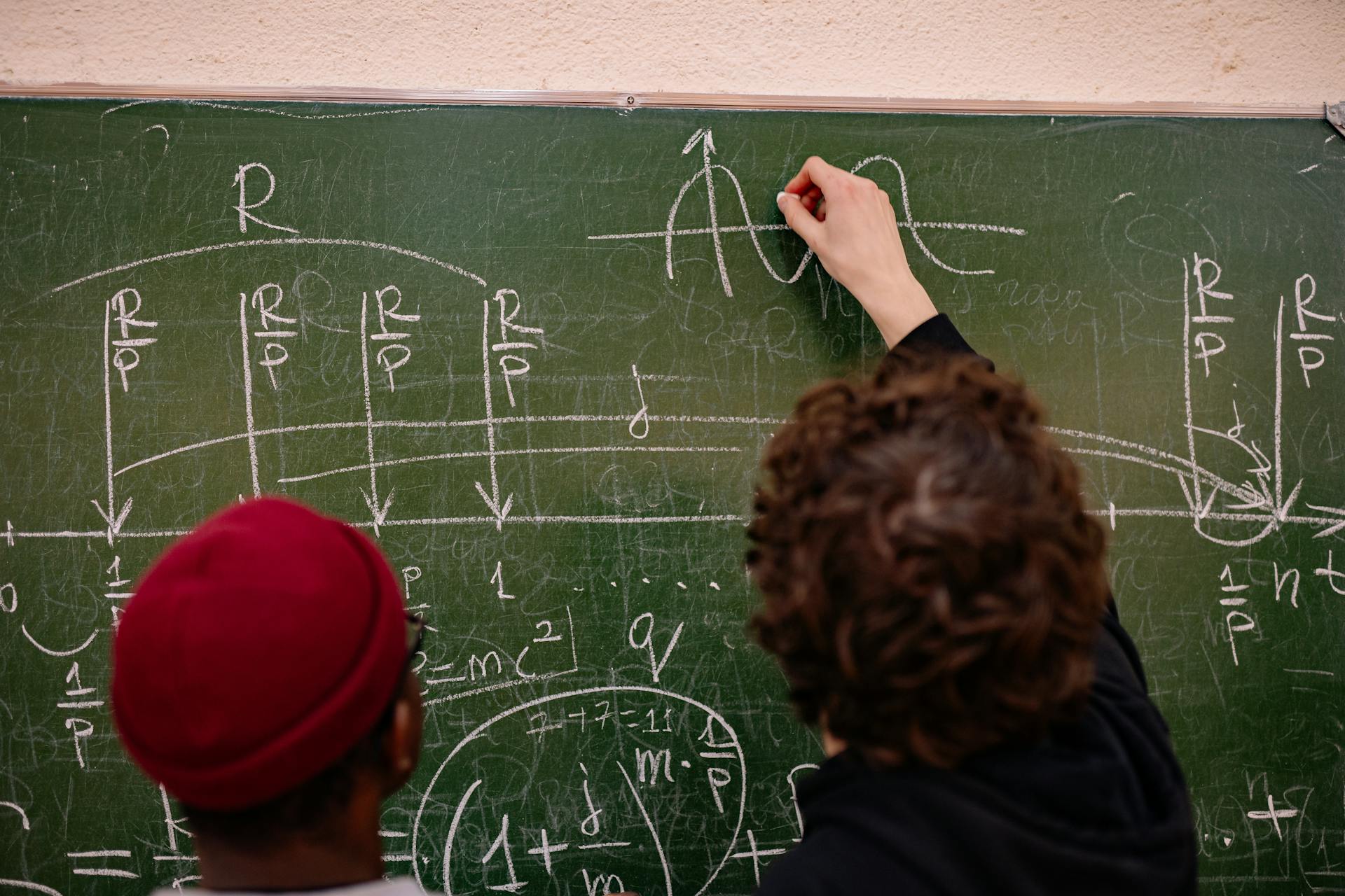 Students working together on complex math problems on a chalkboard.