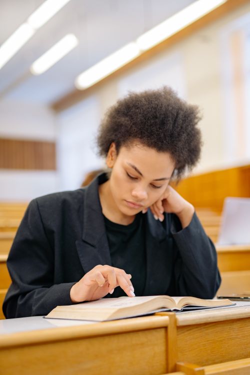 Free Young woman reads intently in a classroom setting, emphasizing study and focus. Stock Photo