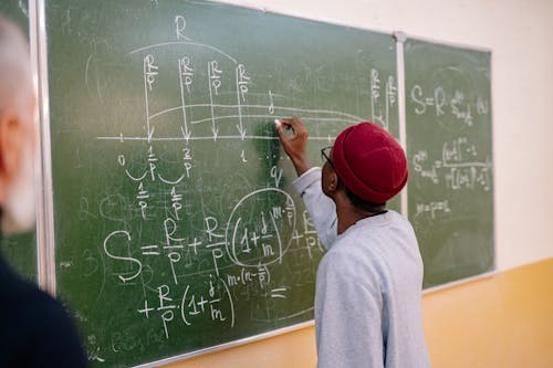 Free Man in Red Cap and Gray Shirt Writing on Chalk Board Stock Photo