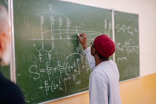 Back View of a Person Writing on a Blackboard