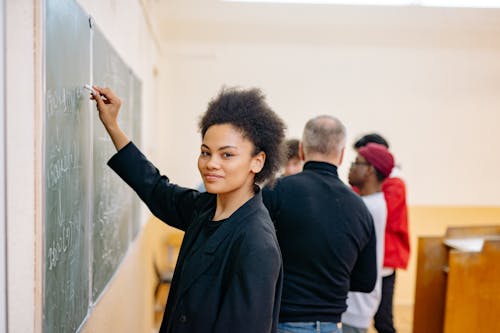 Woman in Black Blazer Wring on a Blackboard