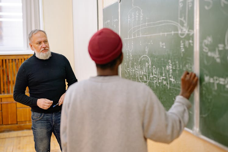 Student And Teacher Looking At The Blackboard