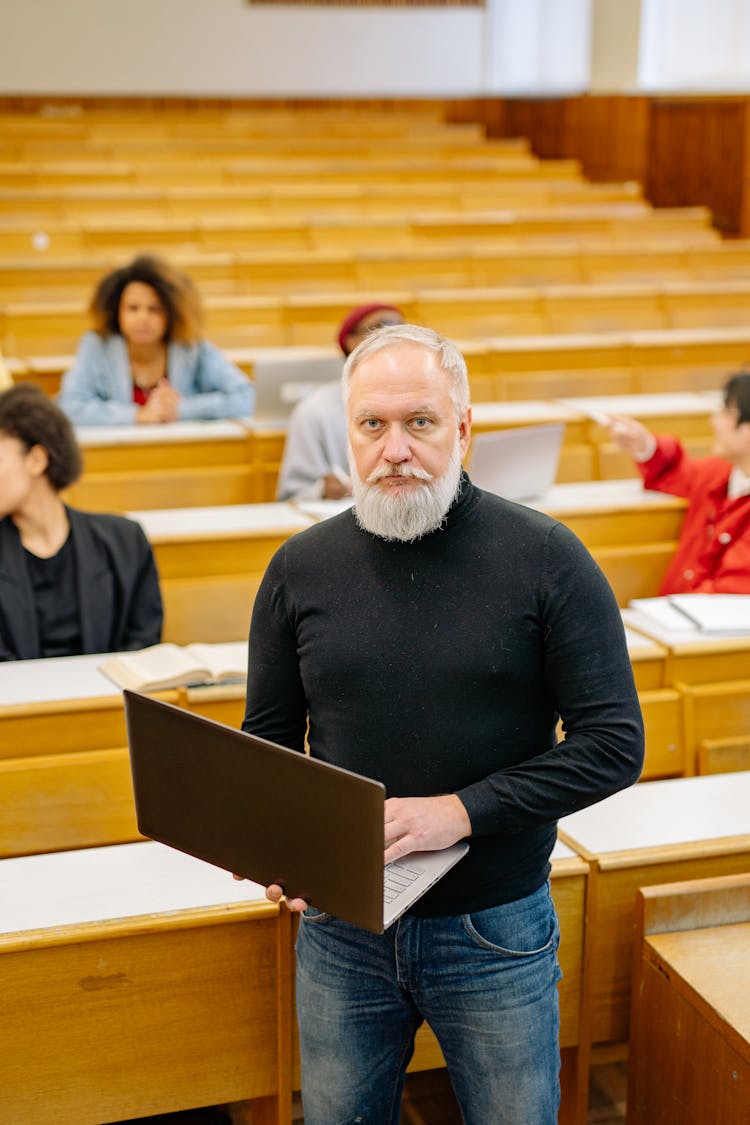 Teacher Holding A Laptop While In The Classroom