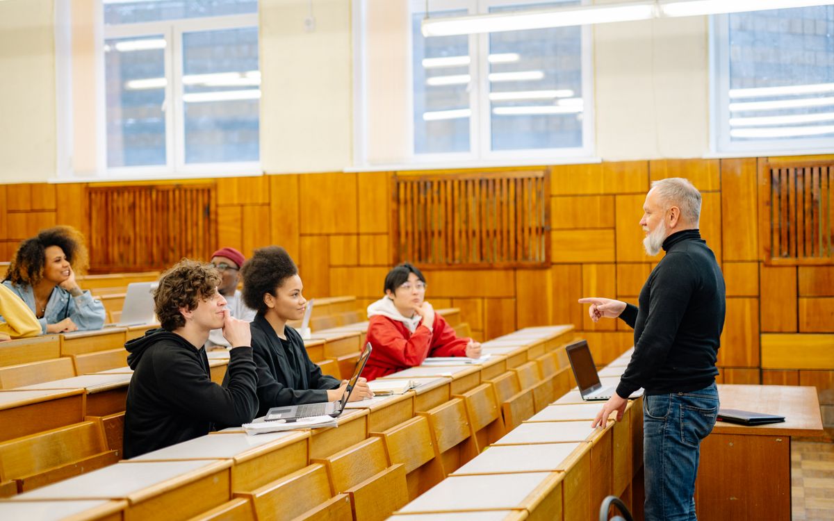 A diverse group of university students engaging with a professor during a classroom lecture.