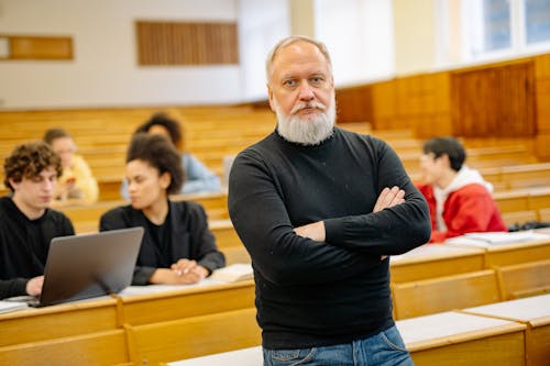 Professor Standing in a Lecture Hall on the Background of Students Sitting at the Desks 