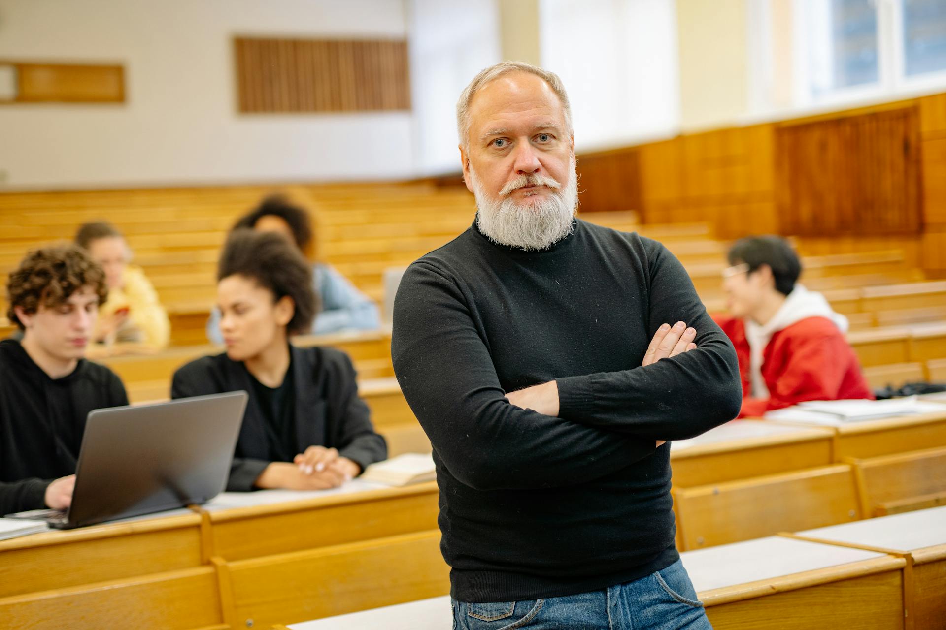 Professor Standing in a Lecture Hall on the Background of Students Sitting at the Desks