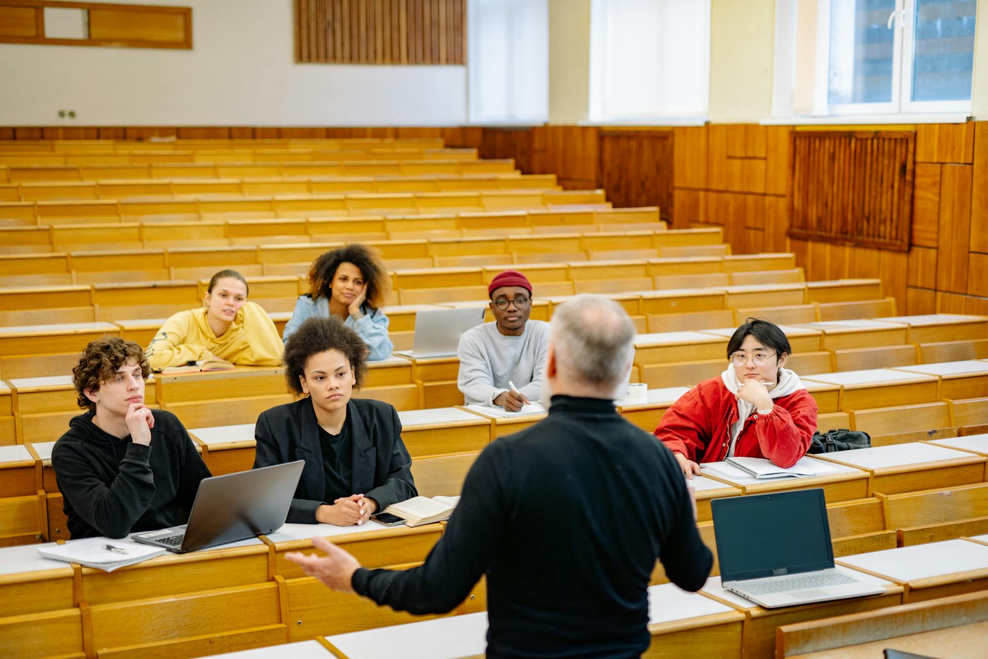 Professor teaching a diverse group of students in a university lecture hall.