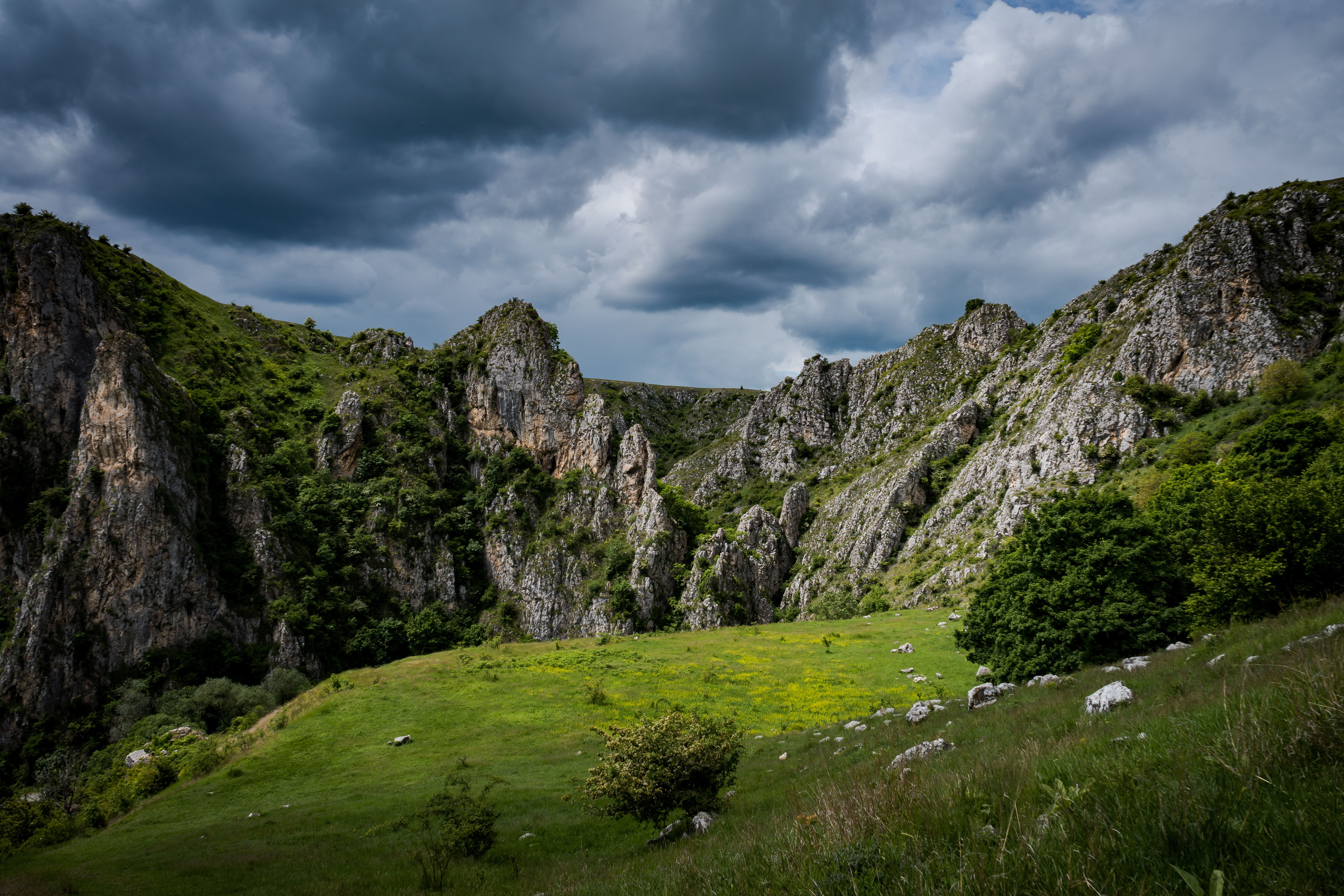 Green Grass Field Near Gray Rocky Mountain Under White Cloudy Sky ...