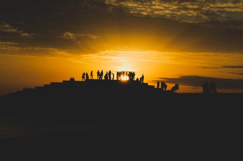 Free Silhouetted figures gather under a vibrant sunset in Durrës, Albania. Stock Photo